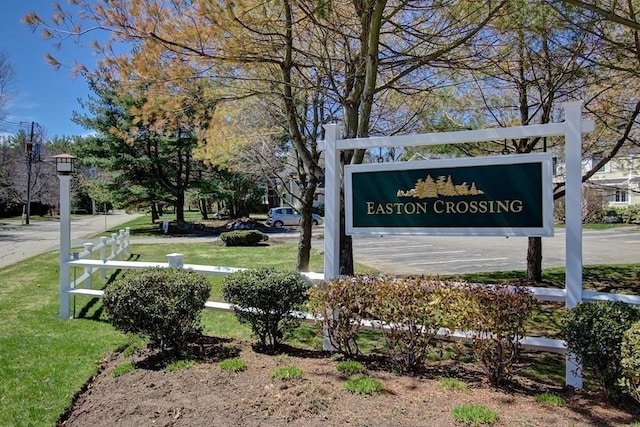 community sign featuring uncovered parking and a yard