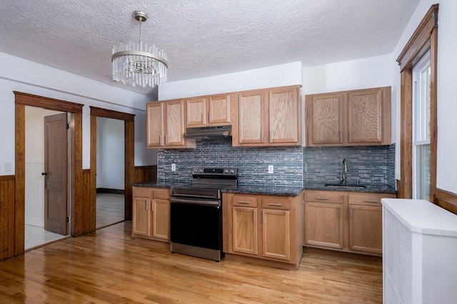 kitchen featuring sink, hanging light fixtures, light hardwood / wood-style floors, stainless steel range oven, and a chandelier