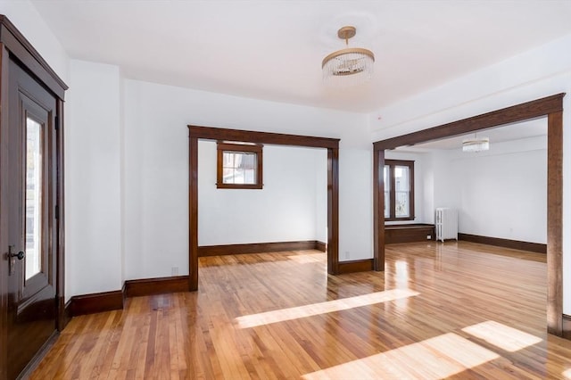 foyer with radiator heating unit, light hardwood / wood-style floors, and an inviting chandelier