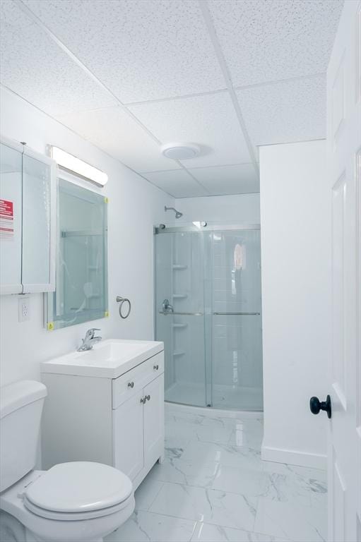 bathroom with a paneled ceiling, vanity, toilet, and walk in shower