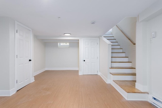 basement featuring wood-type flooring and a baseboard heating unit