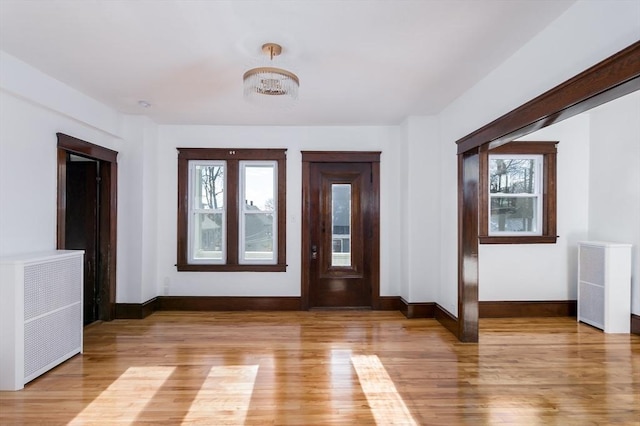 entrance foyer featuring a chandelier, radiator heating unit, and hardwood / wood-style flooring