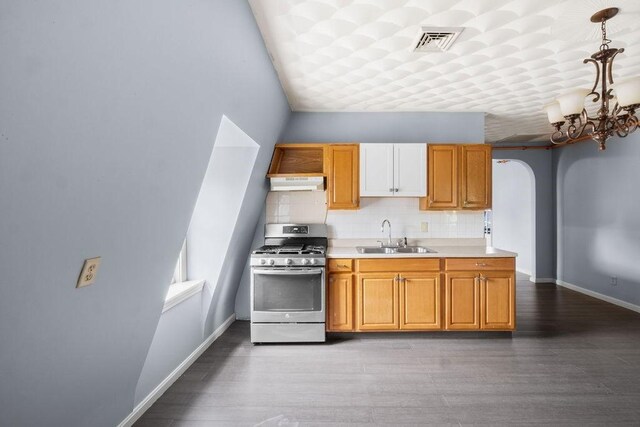 186 John St, Fall River, MA 02721 - kitchen with gas range, a sink, under cabinet range hood, light countertops, and decorative backsplash
