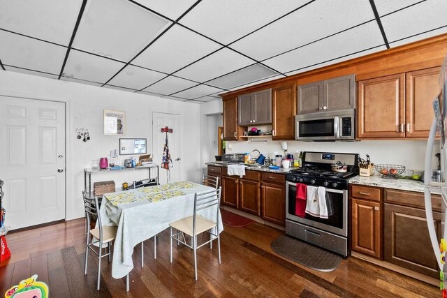186 John St, Fall River, MA 02721 - kitchen featuring appliances with stainless steel finishes, a paneled ceiling, dark wood-type flooring, open shelves, and brown cabinets