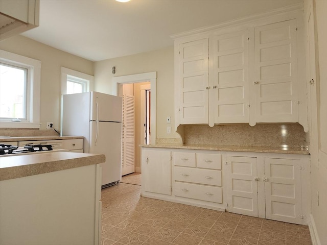 235 Common St, Watertown, MA 02472 - kitchen featuring freestanding refrigerator, light countertops, and white cabinets