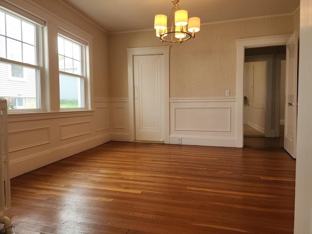 235 Common St, Watertown, MA 02472 - unfurnished dining area with a chandelier, wood finished floors, crown molding, wainscoting, and a decorative wall