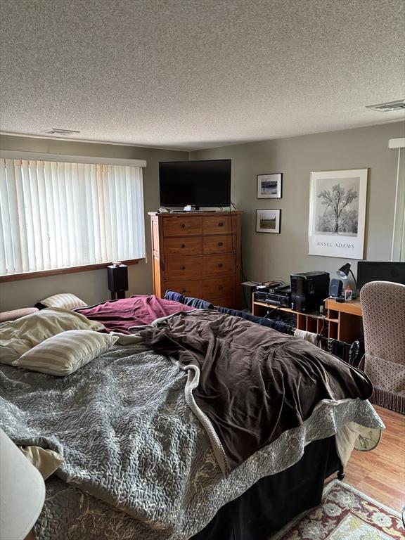 bedroom with a textured ceiling and hardwood / wood-style flooring