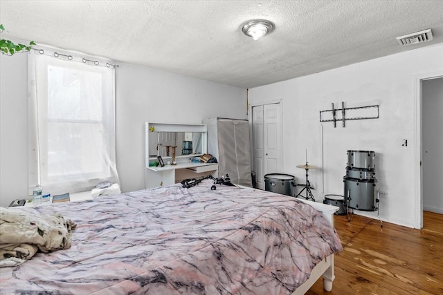 bedroom with hardwood / wood-style floors, a closet, and a textured ceiling