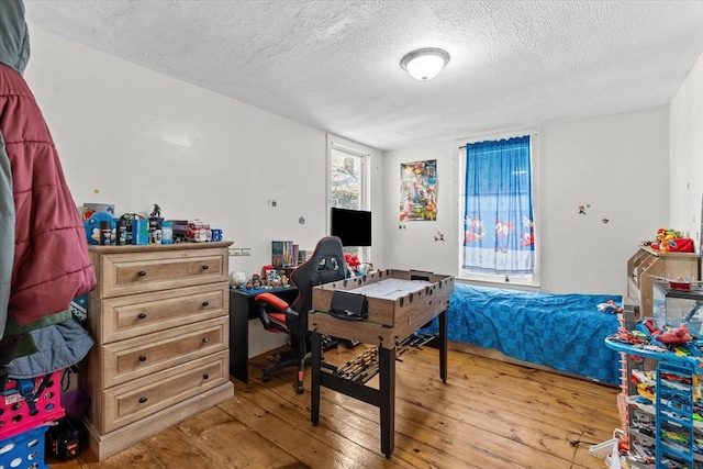 bedroom with access to exterior, light hardwood / wood-style flooring, and a textured ceiling