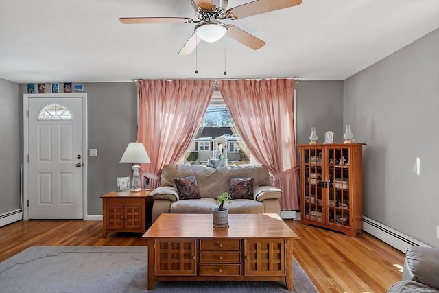 living room featuring light wood-type flooring, ceiling fan, and baseboard heating