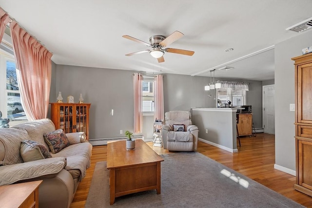 living room with a baseboard radiator, ceiling fan, and light wood-type flooring