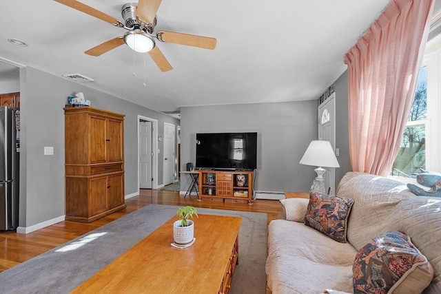 living room featuring light wood-type flooring, ceiling fan, and baseboard heating