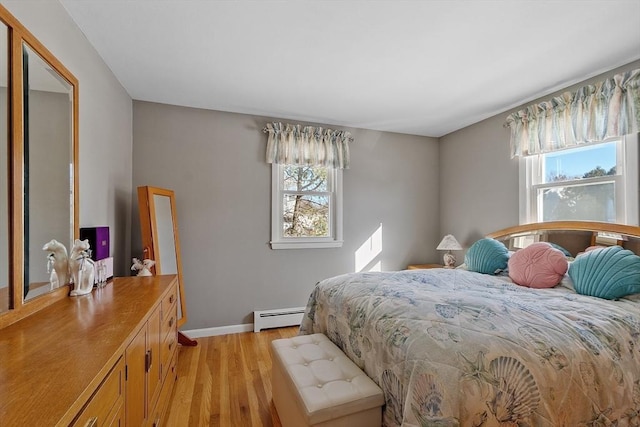 bedroom with a baseboard heating unit and light wood-type flooring