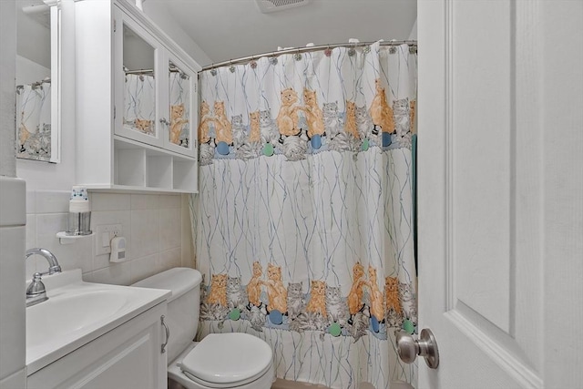 bathroom with vanity, toilet, decorative backsplash, and tile walls