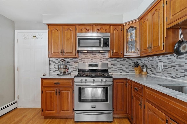 kitchen featuring a baseboard heating unit, decorative backsplash, stainless steel appliances, and light wood-type flooring