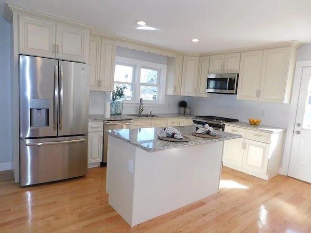 15 Phillips St, Weymouth, MA 02188 - kitchen featuring stainless steel appliances, a sink, light stone counters, light wood-style flooring, and a kitchen island
