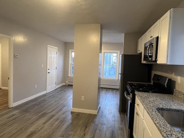 kitchen featuring light stone countertops, white cabinetry, stainless steel microwave, and gas stove