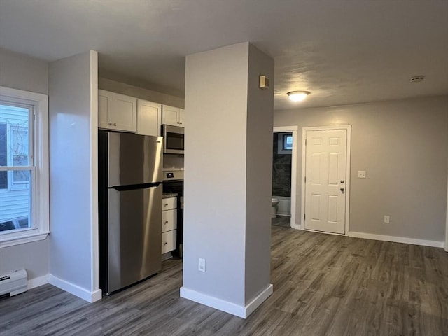 kitchen with dark countertops, appliances with stainless steel finishes, dark wood-type flooring, white cabinetry, and baseboards