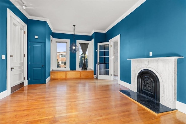 unfurnished living room featuring a fireplace, crown molding, baseboards, and wood finished floors