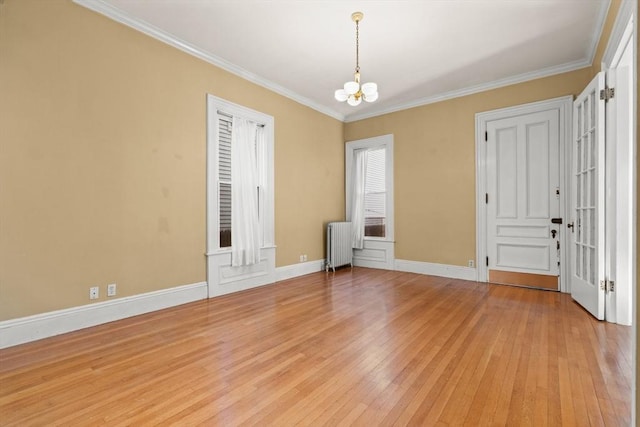 unfurnished room with a chandelier, light wood-style floors, baseboards, ornamental molding, and radiator