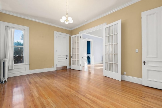 unfurnished room featuring french doors, crown molding, light wood finished floors, radiator heating unit, and an inviting chandelier