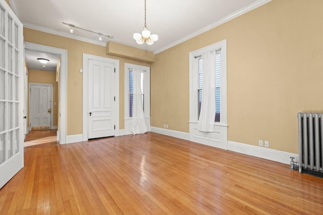 foyer with ornamental molding, radiator heating unit, light wood-style flooring, and an inviting chandelier