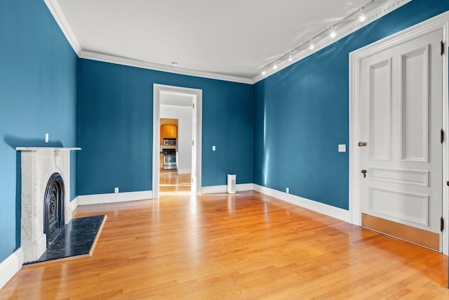 unfurnished living room featuring baseboards, ornamental molding, wood finished floors, and a high end fireplace