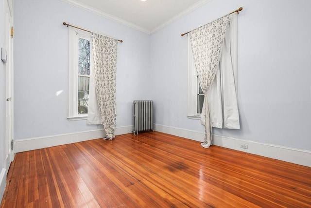 spare room with wood-type flooring, baseboards, crown molding, and radiator heating unit