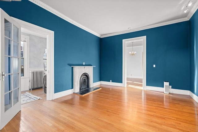 unfurnished living room featuring ornamental molding, hardwood / wood-style floors, radiator heating unit, and a chandelier