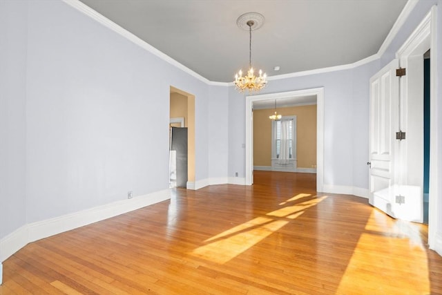 unfurnished dining area with crown molding, baseboards, wood finished floors, and a notable chandelier