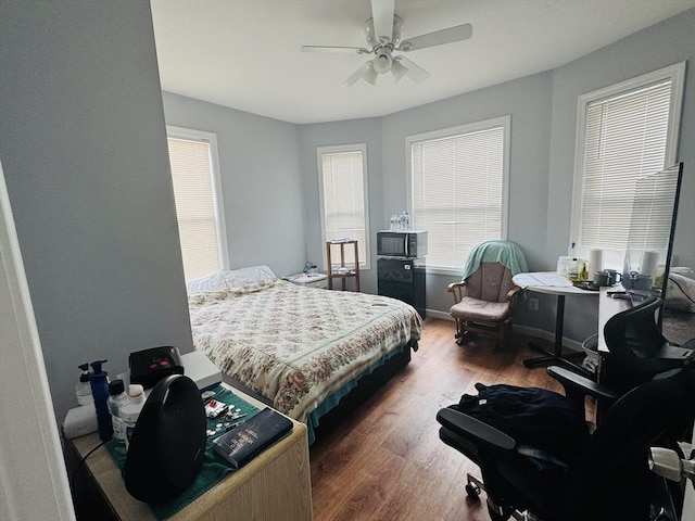 bedroom with a ceiling fan, wood finished floors, and baseboards