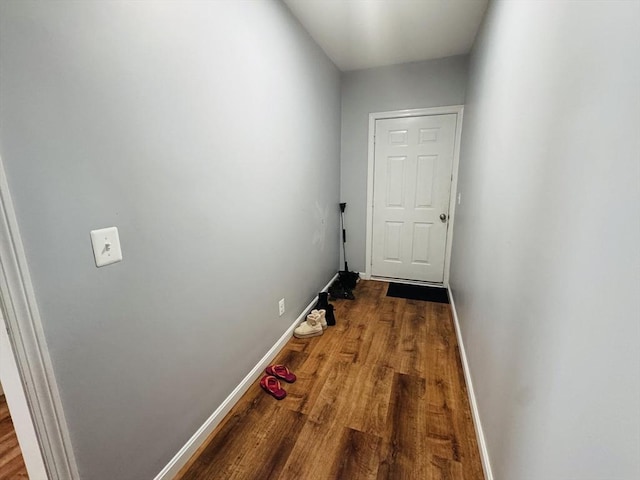 doorway featuring baseboards and wood finished floors