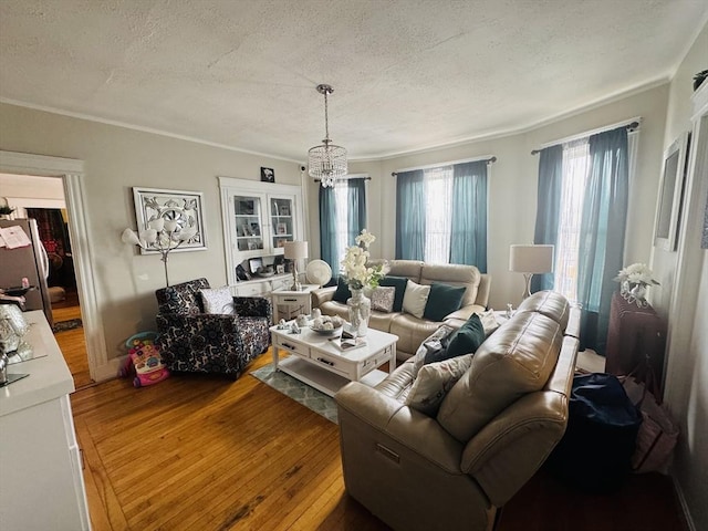 living area featuring hardwood / wood-style flooring, ornamental molding, a chandelier, and a textured ceiling