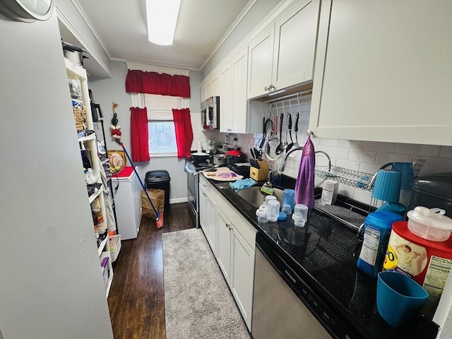 kitchen with backsplash, ornamental molding, appliances with stainless steel finishes, white cabinetry, and dark wood-style flooring