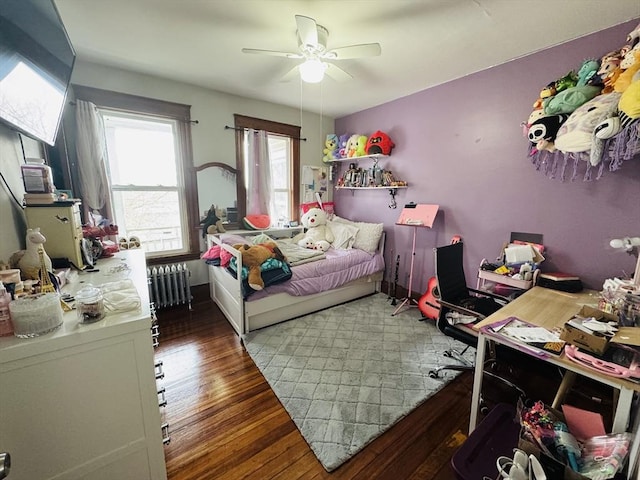 bedroom featuring a ceiling fan, wood finished floors, and radiator heating unit