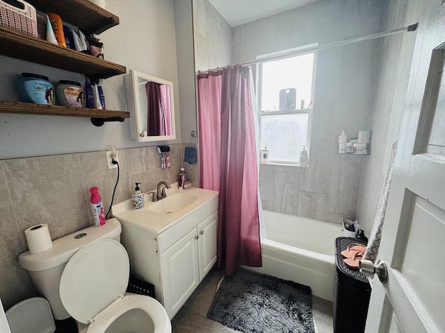 full bathroom with tile walls, a wainscoted wall, toilet, shower / bath combo with shower curtain, and vanity