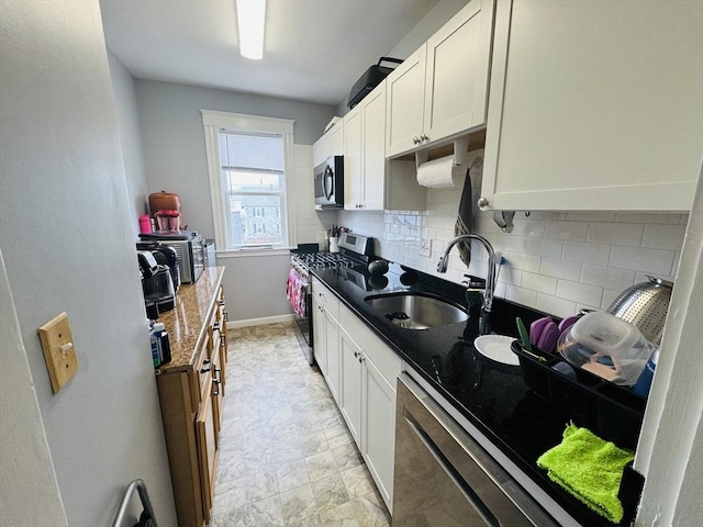 kitchen featuring decorative backsplash, white cabinetry, appliances with stainless steel finishes, and a sink