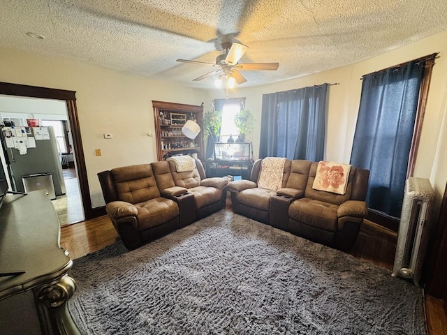 living room with radiator, wood finished floors, a ceiling fan, and a textured ceiling