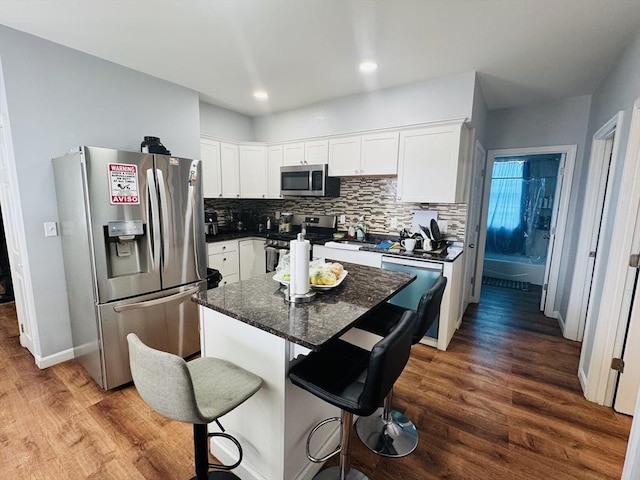 kitchen with stainless steel appliances, dark wood-type flooring, white cabinets, and decorative backsplash