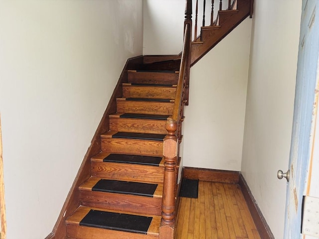 staircase featuring baseboards and wood-type flooring