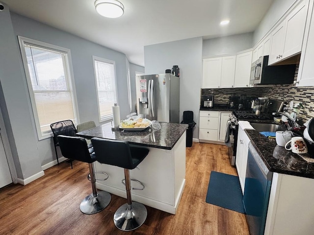 kitchen with white cabinetry, light wood finished floors, tasteful backsplash, and appliances with stainless steel finishes