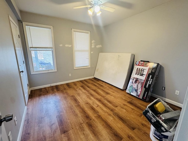 interior space featuring baseboards, wood finished floors, and a ceiling fan