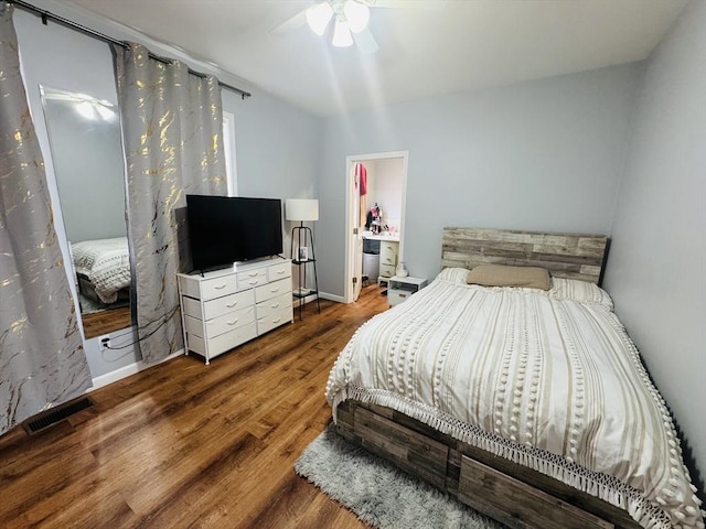 bedroom with a ceiling fan, wood finished floors, visible vents, and baseboards