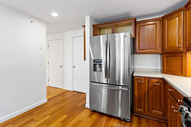 kitchen featuring stainless steel fridge with ice dispenser, stove, and light hardwood / wood-style floors