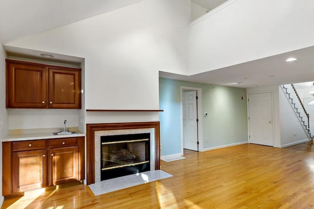 unfurnished living room featuring a premium fireplace, sink, and light wood-type flooring