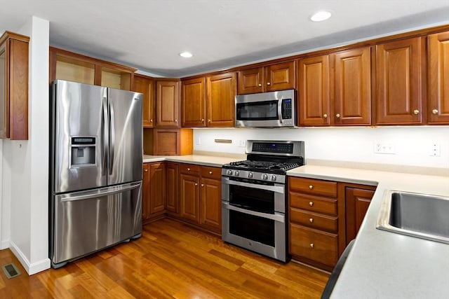 kitchen with hardwood / wood-style floors, appliances with stainless steel finishes, and sink