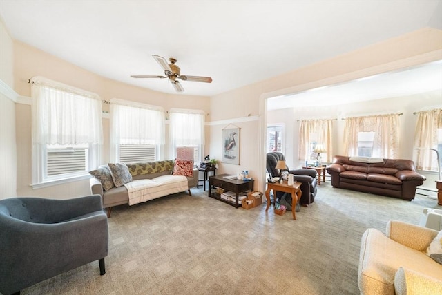 living room with light colored carpet, baseboard heating, ceiling fan, and a healthy amount of sunlight