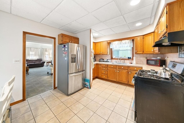 kitchen with black appliances, a paneled ceiling, light tile patterned flooring, and sink