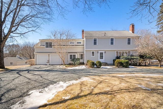 rear view of property with a garage, driveway, and a chimney