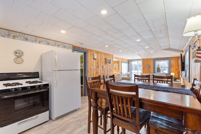 dining space featuring light wood-type flooring and wooden walls